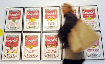 Una mujer camina delante de un trabajo del artista estadounidense Andy Warhol, que muestra las simbólicas latas de sopa Campbell, expuesto en el Museo del Novecento en Milán, Italia. EFE/Archivo