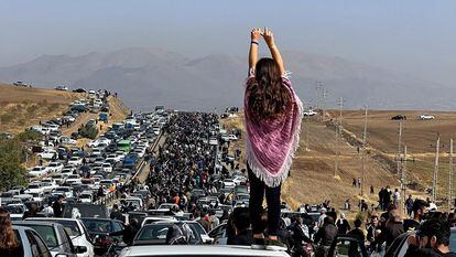 Una mujer sin velo de pie sobre un vehículo mientras miles de personas se dirigen hacia el cementerio de Aichi en Saqez, la ciudad natal de Mahsa Amini, el 26 de octubre de 2022.