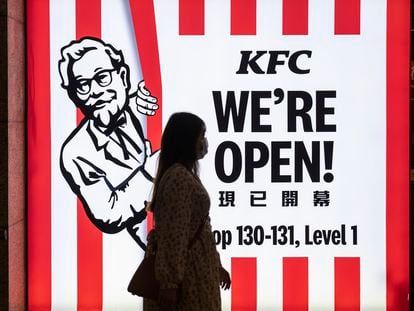 Una mujer camina por delante de un restaurante de la cadena estadounidense KFC  en Hong Kong.