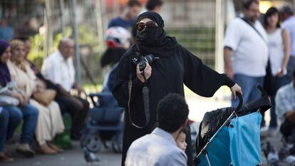Una mujer ataviada con un niqab pasea junto a su familia por la plaza de Catalunya de Barcelona.