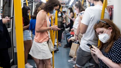 Personas consultan sus teléfonos móviles en un vagón del metro de Madrid.