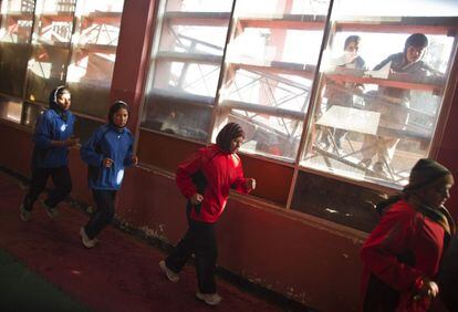 Unos niños miran el entrenamiento de las mujeres boxeadores. Los curiosos se suelen agolpar en las ventanas para verlas entrenar en este espartano gimnasio de la capital afgana.