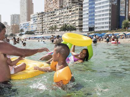 Mario (a la izquierda) juega con Alexander (centro) y Andrea (subida en el flotador), en el agua de la playa de Benidorm.