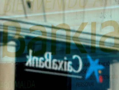 Logotipo de Caixabank reflejado en una ventana de una oficina de Bankia