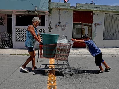 Una mujer y un niño transportan contenedores de agua en un carro de supermercado en Apodaca, Nuevo León, en 2022.