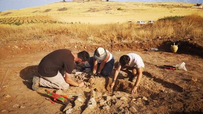 Tres arqueólogos excavan una del centenar de tumbas íberas halladas en la necrópolis de Alarcos. Al fondo, el castillo medieval.