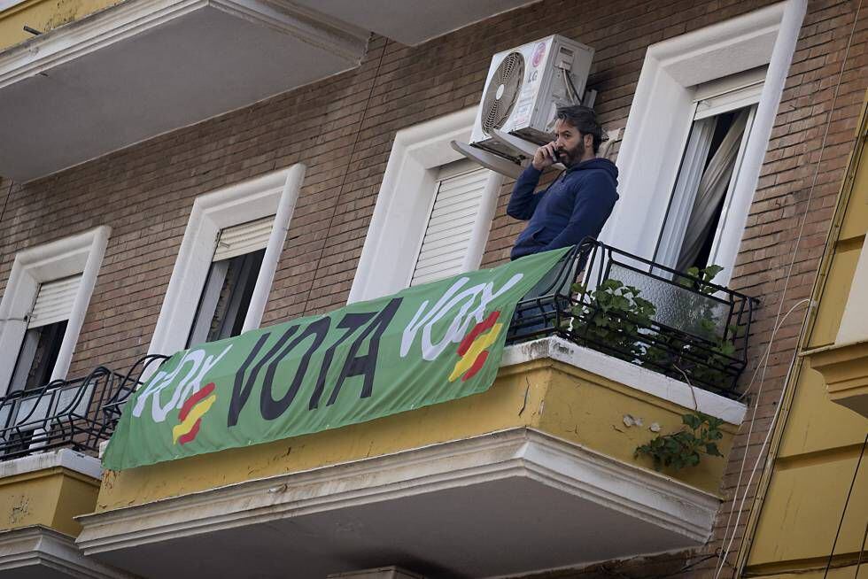 Un hombre en un balcón de Sevilla con una pancarta de Vox.