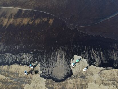 Workers clean oil from Cavero beach in Ventanilla, Callao, Peru, Tuesday, Jan. 18, 2022, after high waves attributed to the eruption of an undersea volcano in Tonga caused an oil spill. The Peruvian Civil Defense Institute said in a press release that a ship was loading oil into La Pampilla refinery on the Pacific coast on Sunday when strong waves moved the boat and caused the spill. (AP Photo/Martin Mejia)