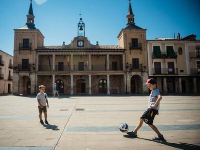 Dos niños juegan al fútbol en la plaza del Burgo de Osma, en Soria.