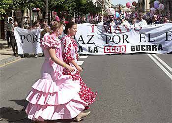 Dos jóvenes vestidas de flamencas pasan frente a la cabecera de la manifestación celebrada ayer en Sevilla.