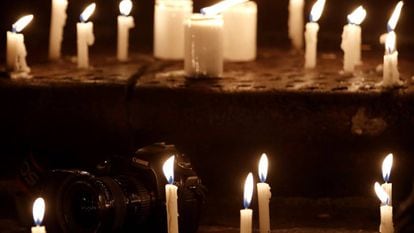 Velas encendidas en torno a una cámara en la vigilia en homenaje a los periodistas asesinados.