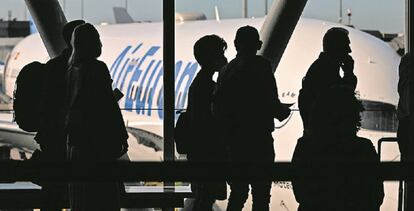 Viajeros en la T4 de Madrid-Barajas con un avión de Air Europa de fondo.