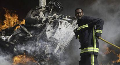 Un bombero trata de apagar el fuego dejado por la explosi&oacute;n.