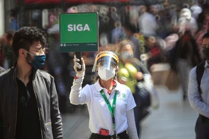 Una funcionaria sostiene un cartel para evitar aglomeraciones en Ciudad de México.