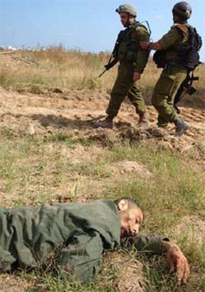 Dos soldados israelíes pasan en Gaza ante un palestino muerto.