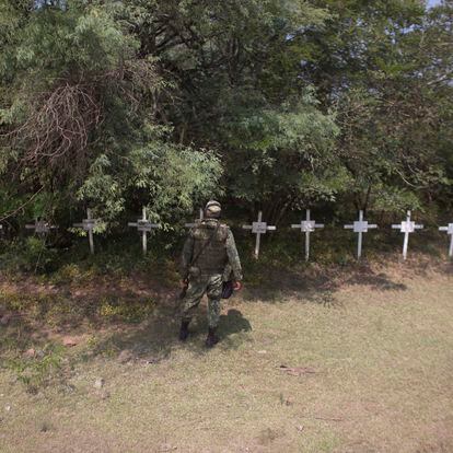 In this Oct. 24, 2012 photo, an soldier looks at crosses allegedly left by the drug cartel "Caballeros Templarios," or Knights Templar, that represent members of the cartel who have died, near the town of Cueramato in Michoacan state, Mexico. Knights Templar, a quasi-religious drug cartel that controls the area and most of the state, monitors the movements of the military and police around the clock. The gang's members not only live off methamphetamine and marijuana smuggling and extortion, they maintain country roads, control the local economy and act as private debt collectors for citizens frustrated with the courts, soldiers say.  (AP Photo/Alexandre Meneghini)
