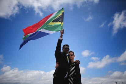 Karlind Govender y su esposa Katharina, de Ciudad del Cabo, se despiden de Nelson Mandela levantando la bandera sudafricana en Qunu mientras tiene lugar el entierro.