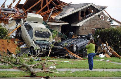 Una mujer habla por teléfono a las afueras de su casa tras el paso de un tornado en Lancaster, Tejas (EE UU).