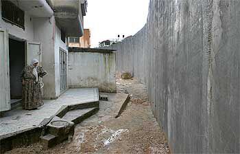 Una mujer palestina observa desde la puerta de su casa el muro construido por Israel.