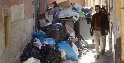 Dos vecinos de M&aacute;laga sortean la basura acumulada ayer en un contenedor por la huelga de los servicios de limpieza