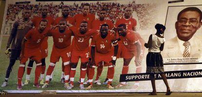 Una mujer mira un póster de la selección de fútbol de Guinea Ecuatorial junto al presidente Obiang.