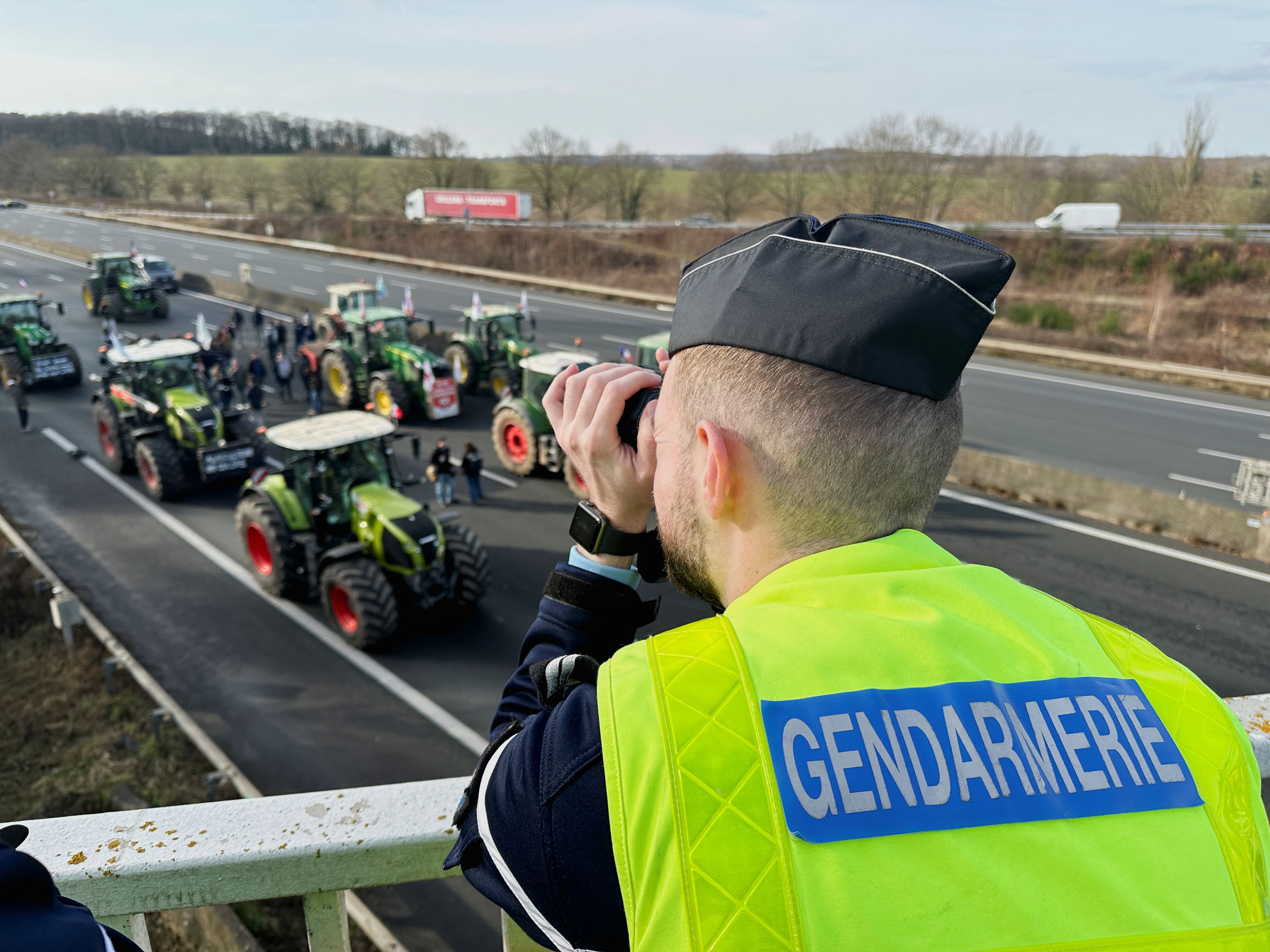Un gendarme vigila la columna de tractores con dirección a París.