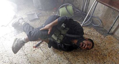 Un combatiente del Ej&eacute;rcito Libre de Siria se duele de una pierna tras ser alcanzado por la metralla en el barrio de Saladino.