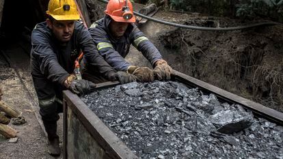 Unos mineros empujan una carretilla con carbón en una mina de Cucunubá, en Colombia.