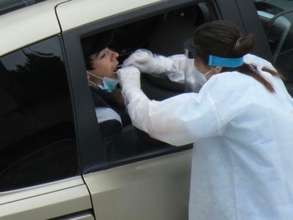 Una trabajadora del hospital de Eibar realiza el test PCR al conductor de un vehículo en el 'parking' del centro.