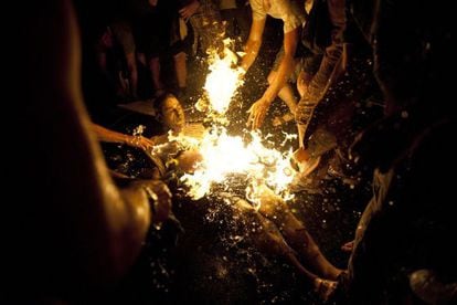 Varias personas intentan apagar las llamas del manifestante que se prendi&oacute; fuego.