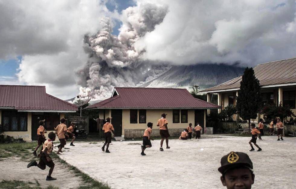 Escolares juegan mientras el volcán Sinabung entra en erupción (Sumatra).