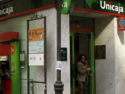 Varias personas utilizan cajeros de una oficina de Unicaja.