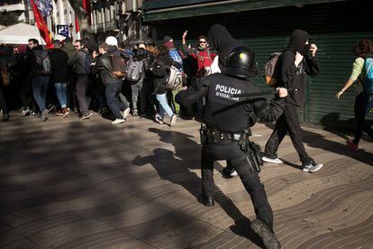 Un policía carga contra los manifestantes conovocados por los CDR, en Las Ramblas (Barcelona).