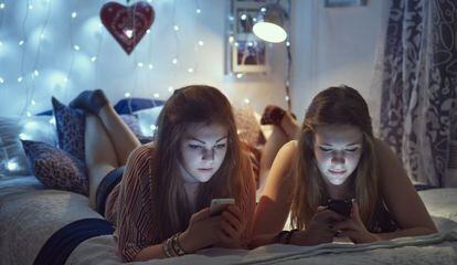 Dos chicas consultan sus móviles.