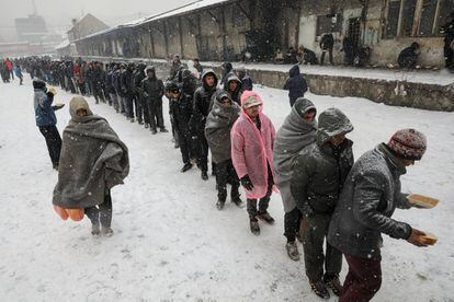 Un grupo de migrantes hacen cola para recibir comida en un edificio abandonado en Belgrado (Serbia).