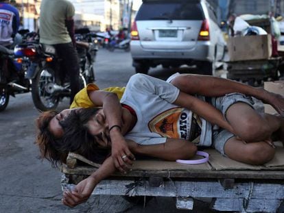 Dos personas duermen en la calle, sobre una carretilla en el mercado callejero de Divisioria, en el distrito de Tondo, en Manila.