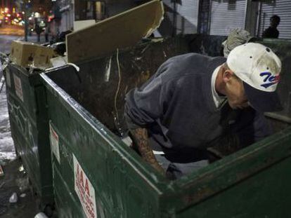 Un vagabundo busca comida en un contenedor de basura en Los &Aacute;ngeles