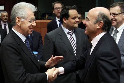 Luis de Guindos, ministro de Economía español, saluda al Primer Ministro de Italia, Mario Monti, ayer en Bruselas.