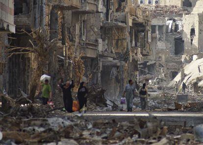 Residentes y un combatiente rebelde atraviesan una zona residencial devastada en Deir al Zor (este de Siria), el 7 de abril.