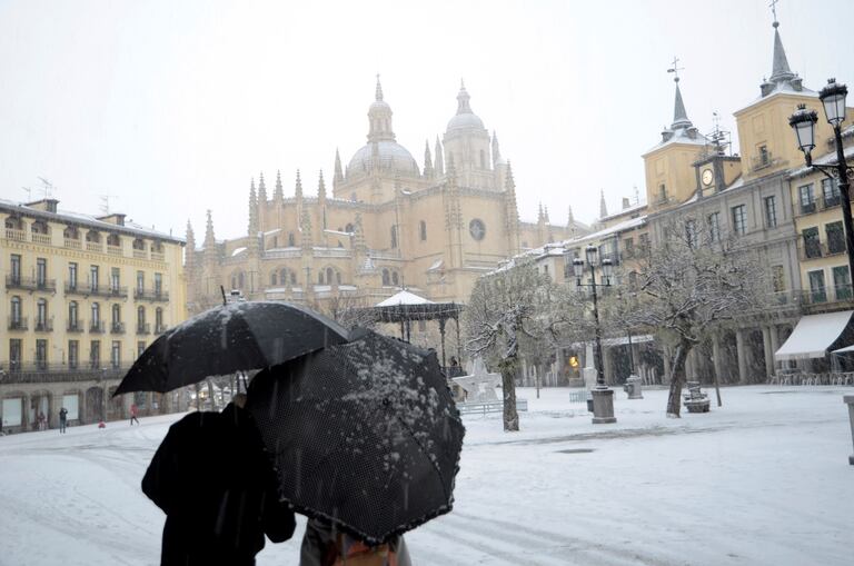 GRAF7184. SEGOVIA, 08/01/2021.- Dos personas caminan por la Plaza Mayor de Segovia durante una intensa nevada, este viernes, jornada marcada por el paso de la borrasca Filomena. EFE/ Pablo Martín