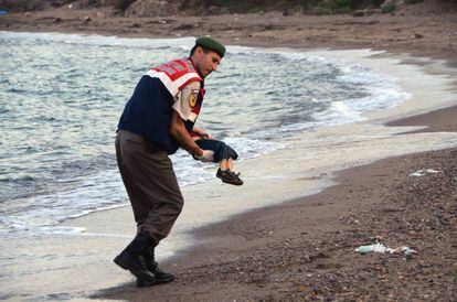Un polic&iacute;a paramilitar sostiene el cuerpo sin vida de Aylan, ni&ntilde;o inmigrante ahogado en una playa de Turqu&iacute;a.