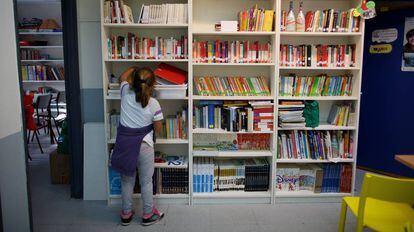 Una niña recoge un libro en un centro educativo.