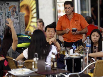 Un camarero cobra a un grupo de turistas en una terraza del centro de Madrid.