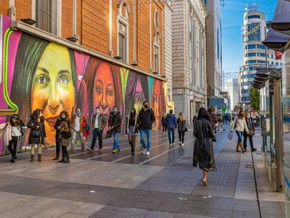 Personas con mascarilla pasean por la Gran Vía de Madrid junto al mural Nosotras Juntas que homenajea a activistas del feminismo. Getty Images