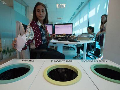 Una trabajadora de la empresa de cosmética Yves Rocher tira un papel en las papeleras de reciclaje que hay en las oficinas de la compañía en Madrid.
