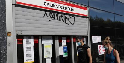 Dos jóvenes pasan ante una oficina de empleo en Madrid.