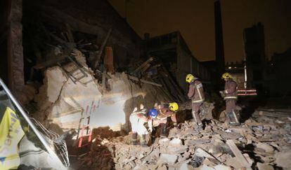 Cuatro agentes de los Bomberos de la Generalitat, ayer por la noche entre los escombros del edificio derrumbado en Sabadell.