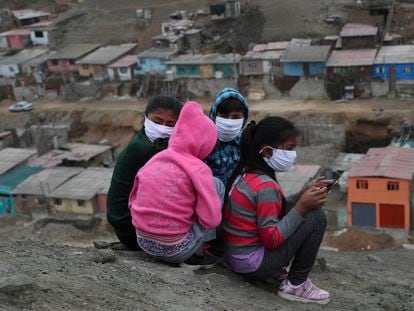 Niños con máscaras para prevenir la propagación del nuevo coronavirus, reciben clases virtuales a través de sus teléfonos móviles sentados en lo alto de una colina en el barrio de Puente Piedra, en las afueras de Lima, Perú.