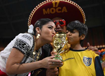 Seguidores de Ecuador besan una réplica del trofeo en el  estadio Al-Bayt.