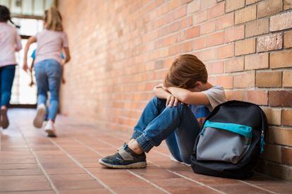 Un menor sentado en el suelo, tras ser víctima de un episodio de acoso escolar.